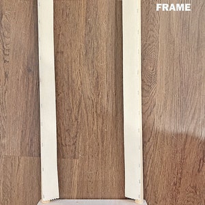 May include: A 20-inch wooden scroll frame with white fabric stretched across it. The frame has two wooden dowels and black metal clamps on each side.