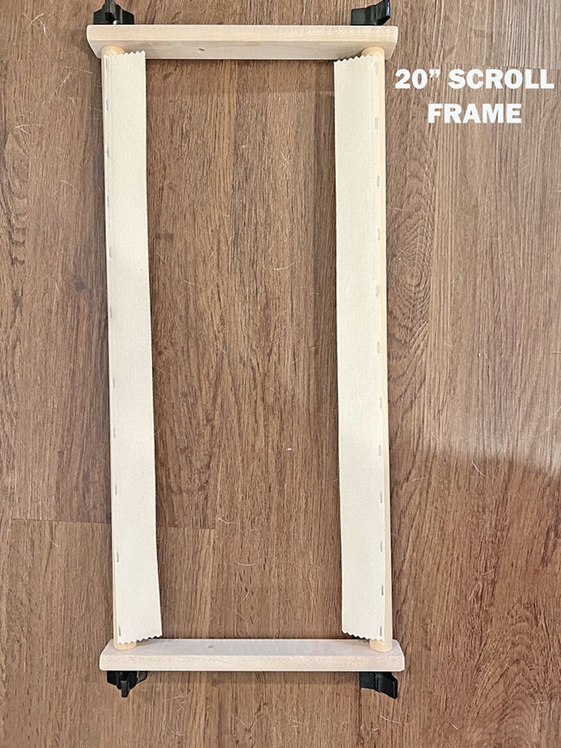 May include: A 20-inch wooden scroll frame with white fabric stretched across it. The frame has two wooden dowels and black metal clamps on each side.