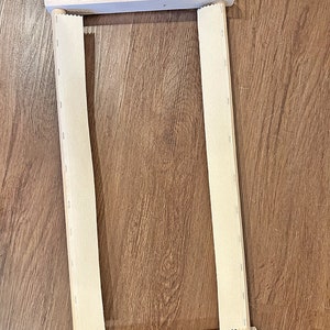May include: An 18 inch wooden scroll frame with a beige fabric stretched across it. The frame has two wooden dowels and black metal clamps on each side.