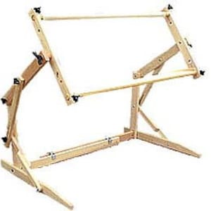 May include: A wooden embroidery hoop stand with adjustable height and angle. The stand has a sturdy base and is designed to hold embroidery hoops of various sizes.