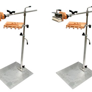 May include: Two silver metal paint roller stands with adjustable height. Each stand has a wooden tray with slots for paint rollers and a clamp for holding a paint roller.