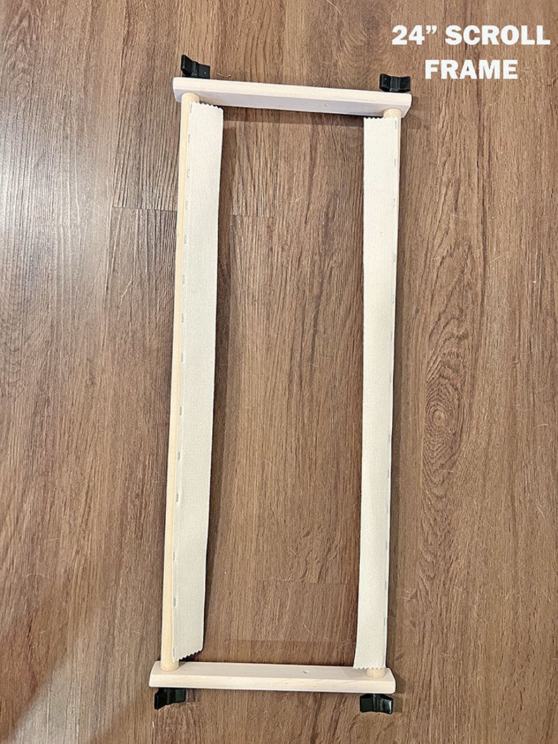May include: A 24-inch wooden scroll frame with white fabric stretched across it. The frame is made of natural wood and has black metal clips at the top and bottom.