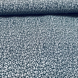 Pode incluir: Um close-up de um tecido azul escuro com um padrão de estampa de leopardo branco.