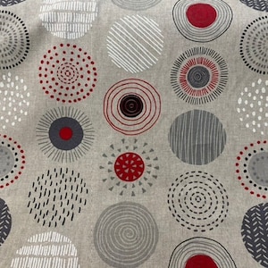 Könnte beinhalten: Ein beigefarbener Stoff mit einem sich wiederholenden Muster aus grauen und roten Kreisen. Die Kreise haben verschiedene Designs, darunter Punkte, Streifen und Spiralen.