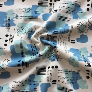 Könnte beinhalten: Weißer Stoff mit einem blauen und grünen geometrischen Muster. Das Muster zeigt abstrakte Formen, Punkte und Linien.
