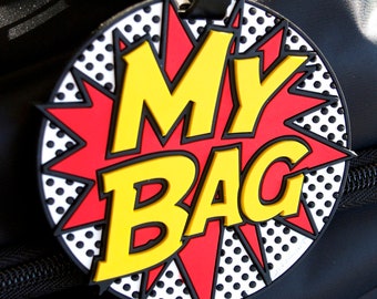Op de afbeelding: Een rode, gele en zwarte bagagelabel met de woorden "MY BAG" in een comic-lettertype.