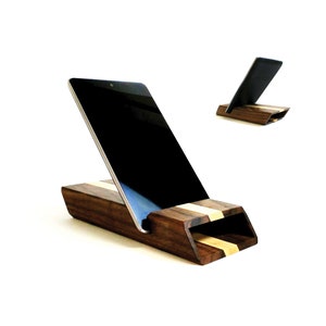 May include: A wooden tablet stand with a dark brown finish and a light wood inlay. The stand is designed to hold a tablet at an angle for viewing.