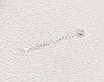 May include: A silver extender chain for jewelry, made of 925 sterling silver. The chain is about 2 inches long and has a lobster clasp.