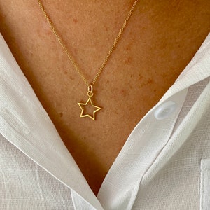 May include: A gold chain necklace with a delicate open star pendant.