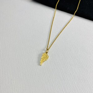 May include: A gold chain necklace with a small, detailed gold wing pendant.