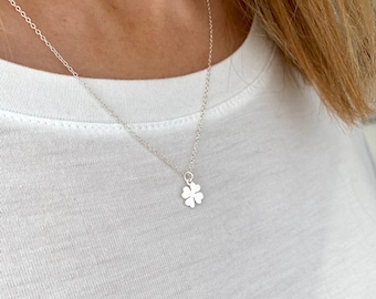 May include: A silver necklace with a four-leaf clover pendant.