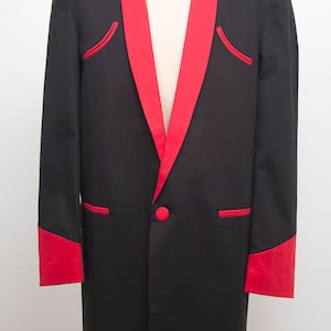 Peut inclure: Un blazer noir avec revers, bordures de poches et poignets en satin rouge. Le blazer a une fermeture à bouton rouge unique et est présenté sur un mannequin. Le design présente une silhouette classique et ajustée.