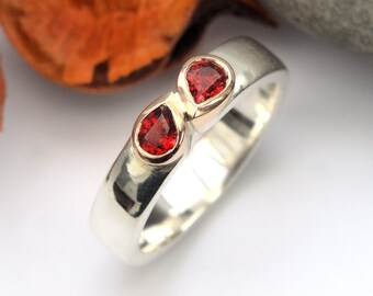 Anillo de compromiso de oro y plata con zafiro rojo y naranja, gemas de doble pera y banda con textura de mimbre