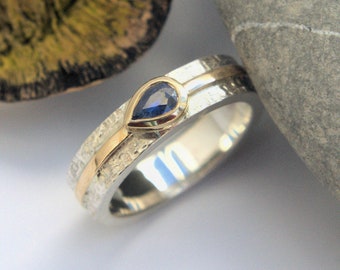 Anillo solitario de oro y plata con zafiro azul, banda con textura de mimbre y detalles de rayas doradas en los hombros. HECHO A PEDIDO.