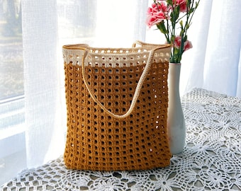 May include: A rectangular crochet tote bag featuring a mustard yellow body with a grid-like openwork pattern and a solid cream-colored top border. The bag includes two matching cream-colored shoulder straps attached to the upper edge.