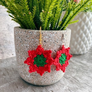 May include: A pair of red and green crocheted flower earrings with gold and silver ear wires.