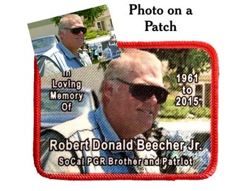 May include: A red embroidered patch with a photo of a man wearing sunglasses. The text on the patch reads "In Loving Memory Of Robert Donald Beecher Jr. SoCal PGR Brother and Patriot 1961 to 2015".