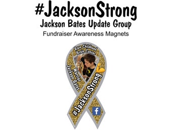 May include: A silver ribbon with gold glitter and a picture of a young boy in the center. The ribbon has the text "#JacksonStrong" and "Warrior Jackson Bates" on it. The ribbon is a symbol of support for those with rare childhood brain cancer.