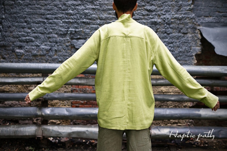 May include: A light green long-sleeved shirt with a high collar and a single button closure at the neck. The shirt is made of a lightweight fabric and has a relaxed fit.