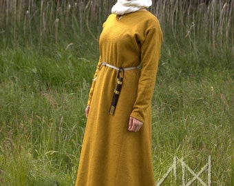 May include: Mustard yellow medieval dress with long sleeves and a matching belt. The dress is worn with a white head covering and scarf. A brown sheath with a dagger is attached to the belt. The dress is made of a thick fabric.