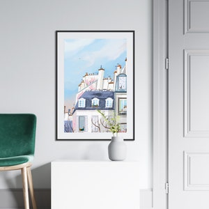 May include: A watercolor painting of a Parisian building with a blue roof and white walls. The building has several windows and a balcony. The painting is framed in black and is hanging on a white wall.