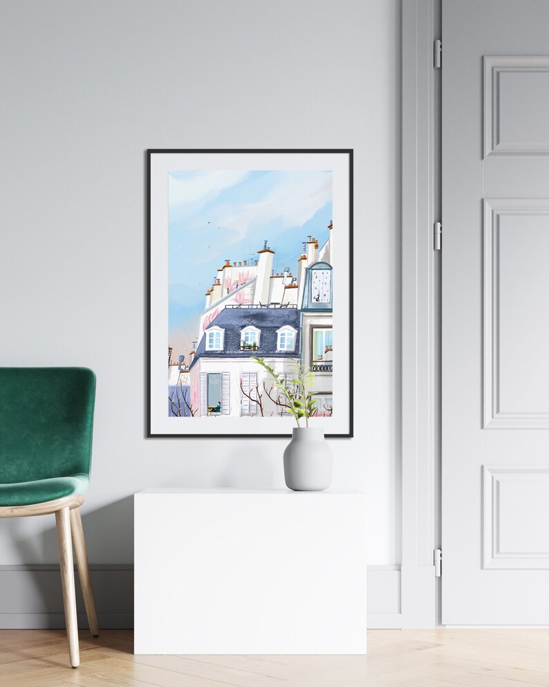 May include: A watercolor painting of a Parisian building with a blue roof and white walls. The building has several windows and a balcony. The painting is framed in black and is hanging on a white wall.