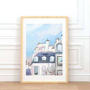 May include: A framed illustration of a Parisian cityscape with white buildings, blue roofs, and pink flowers. The illustration is painted in a watercolor style and features a light blue sky with white clouds.