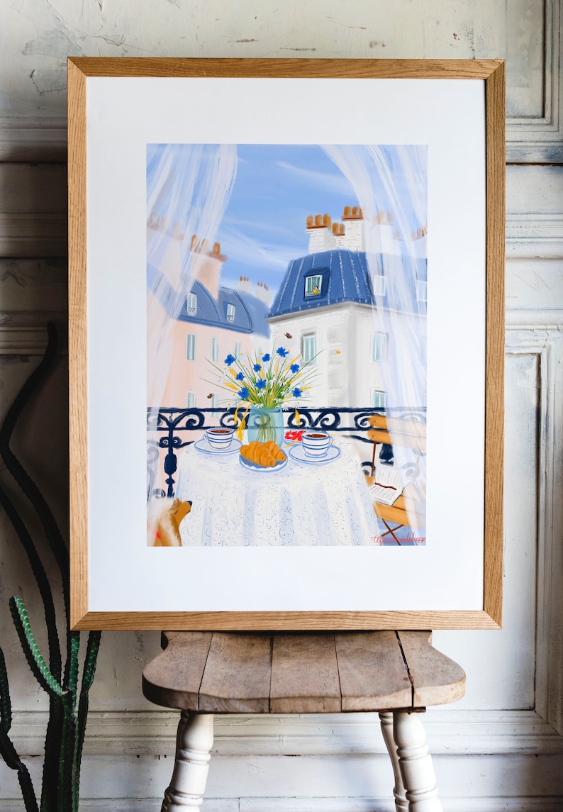 May include: A painting of a Parisian balcony with a white tablecloth, two cups of coffee, a croissant, and a bouquet of blue flowers. A dog is sitting on the balcony floor.
