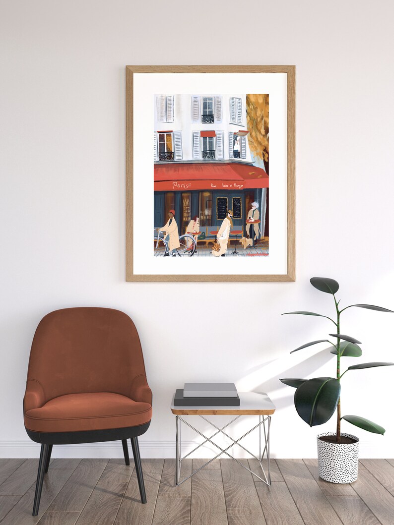 May include: A framed illustration of a Parisian cafe with a red awning that says "Paris" and "Le Bar et Mange". The cafe is on a street corner with people walking by and a bicycle parked in front.