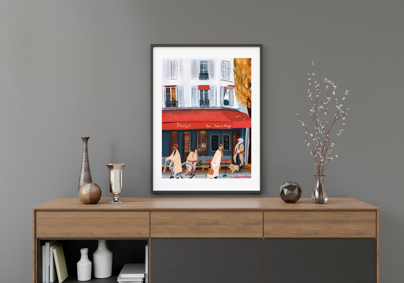 May include: A framed illustration of a Parisian cafe with a red awning and people walking by. The cafe is called "Paris" and has a sign that says "Wine & Cheese".