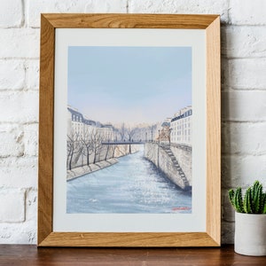 Peut inclure: Une peinture &agrave; l'aquarelle encadr&eacute;e d'une sc&egrave;ne de rue parisienne avec un pont au-dessus d'un canal. Les b&acirc;timents sont blancs et l'eau est bleue. Le ciel est bleu clair.