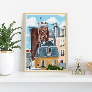 May include: A framed illustration of a Parisian cityscape with a blue sky, white clouds, and a bird flying overhead. The buildings are painted in shades of yellow, orange, brown, and grey. The illustration is framed in a light wood frame.