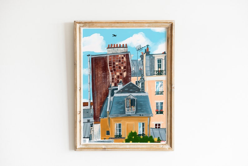 May include: A framed painting depicting a Parisian cityscape with a blue sky, white clouds, and a bird in flight. The painting features a yellow building with a blue roof and a window with a balcony. The building is surrounded by other buildings with red brick and grey stone.