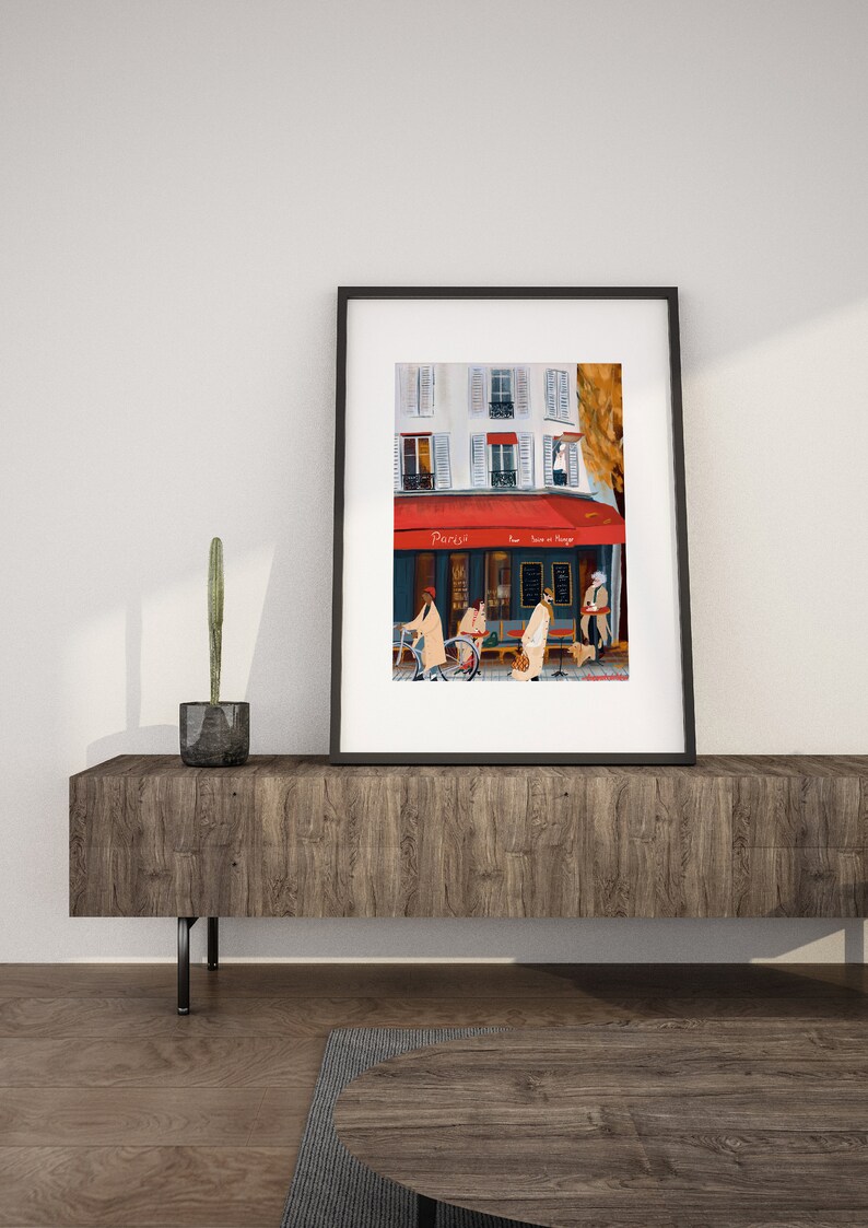 May include: A framed painting of a Parisian street scene with a cafe called "Parisya" with a red awning. People are walking by the cafe, and there is a bicycle parked in front of it.