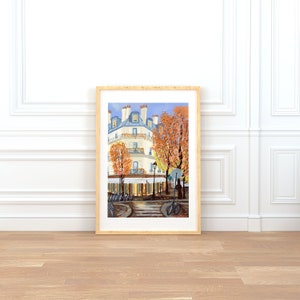 May include: A painting of a Parisian street scene with a white building, a cafe, and bicycles. The building has a blue roof and a balcony. The cafe has a sign that says "P&acirc;tisserie". The street is lined with trees with orange leaves.