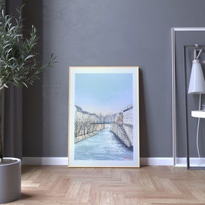 Peut inclure: Une peinture encadr&eacute;e repr&eacute;sentant une ville avec une rivi&egrave;re qui la traverse. Les b&acirc;timents sont blancs et la rivi&egrave;re est bleue. Le ciel est bleu clair. La peinture est dans un cadre dor&eacute;.