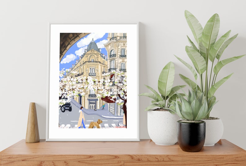 May include: A digital illustration of a Parisian street scene with a woman walking a dog. The buildings are yellow with white trim and there are trees with white blossoms. The sky is blue with white clouds.