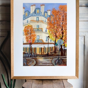 May include: A painting of a Parisian street scene with a cafe, bicycles, and trees with orange leaves. The cafe has a sign that reads " Boulangerie" and "Salon de The".