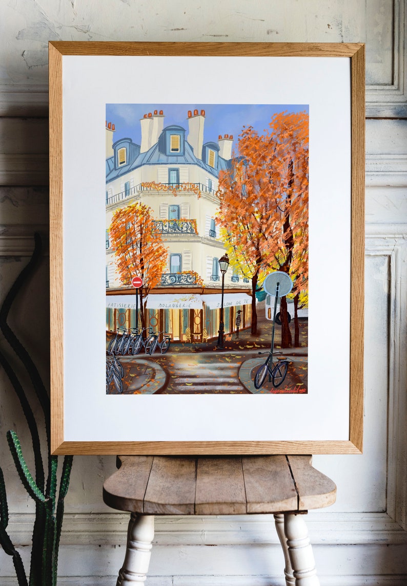 May include: A painting of a Parisian street scene with a cafe, bicycles, and trees with orange leaves. The cafe has a sign that reads " Boulangerie" and "Salon de The".