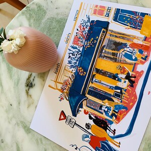 Puede incluir: Una ilustraci&oacute;n colorida de una cafeter&iacute;a con gente sentada en mesas. La cafeter&iacute;a est&aacute; pintada en tonos de azul, amarillo y rojo. La ilustraci&oacute;n est&aacute; impresa en una tarjeta blanca.