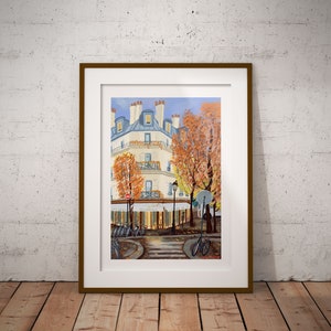 May include: A framed painting of a Parisian street scene with a cafe, bicycles, and a building with a blue roof. The trees are in autumn colors, and the sky is blue.