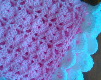 May include: A pink crocheted baby blanket with a white crocheted border.