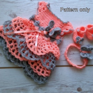 May include: Crochet pattern for a baby dress, headband, and shoes. The dress is pink and gray with a ruffled skirt. The headband and shoes are gray with pink accents. The pattern is for sale, not the finished items.