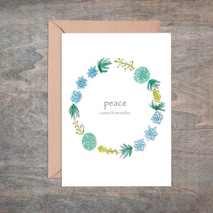 May include: A white card with a green and blue floral wreath around the text "peace comes from within".