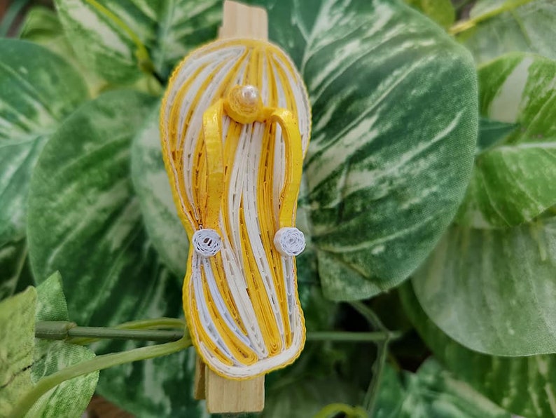 Op de afbeelding: Een gele en witte gestreepte papieren quilling flip-flop met witte parel accenten.