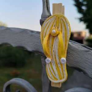 Op de afbeelding: Een gele en witte papieren quilling flip-flop met een parel accent.