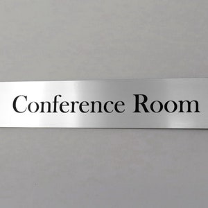 May include: A silver metal sign with the text "Conference Room" in black lettering.