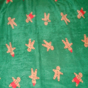 May include: Green fabric with a repeating pattern of gingerbread men. The gingerbread men are brown with red accents.