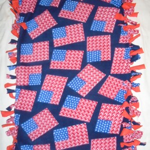 May include: A blue fleece tie blanket with red and blue American flag designs. The blanket is tied with red fringe.