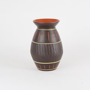 Könnte beinhalten: Eine braune Keramikvase mit strukturierter Oberfläche und orangefarbenen und gelben Streifen.